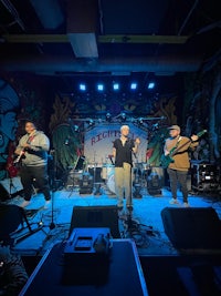 a band performs on stage in front of a mural