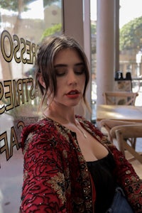 a woman sitting on a bench in front of a coffee shop