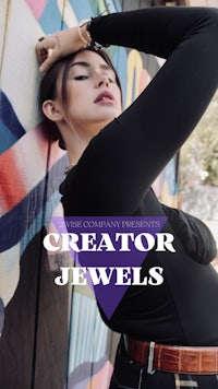 a woman in a black top leaning against a wall with the words creator jewels